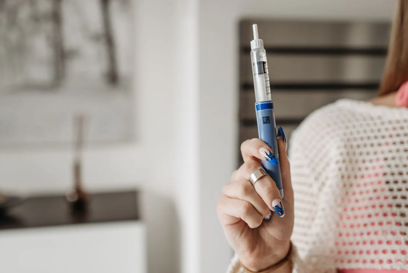 An endocrinologist and a patient sitting together in a bright clinic exam room, reviewing glucose trend charts on a tablet, with a lab report and an injectable pen on the desk between them.